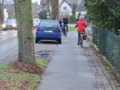 Bild 6: Im Bereich der Einmündung der Rhönstraße wird der schmale Weg regelmäßig durch parkende Kraftfahrzeuge noch weiter eingeengt.